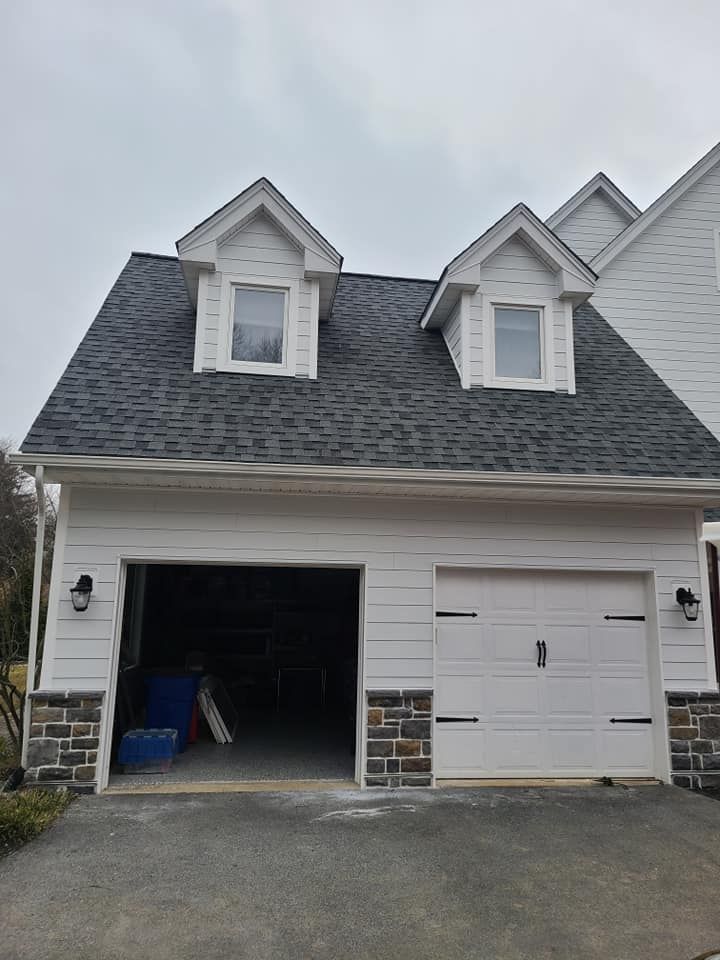 A white house with a garage and a black roof.