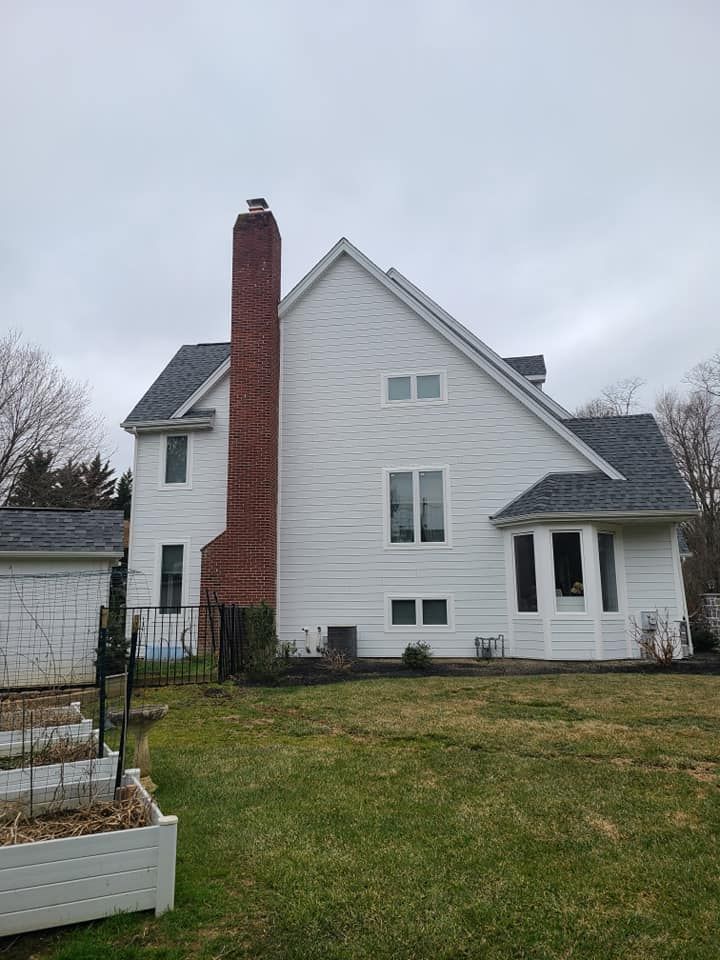A white house with a brick chimney on the side of it.