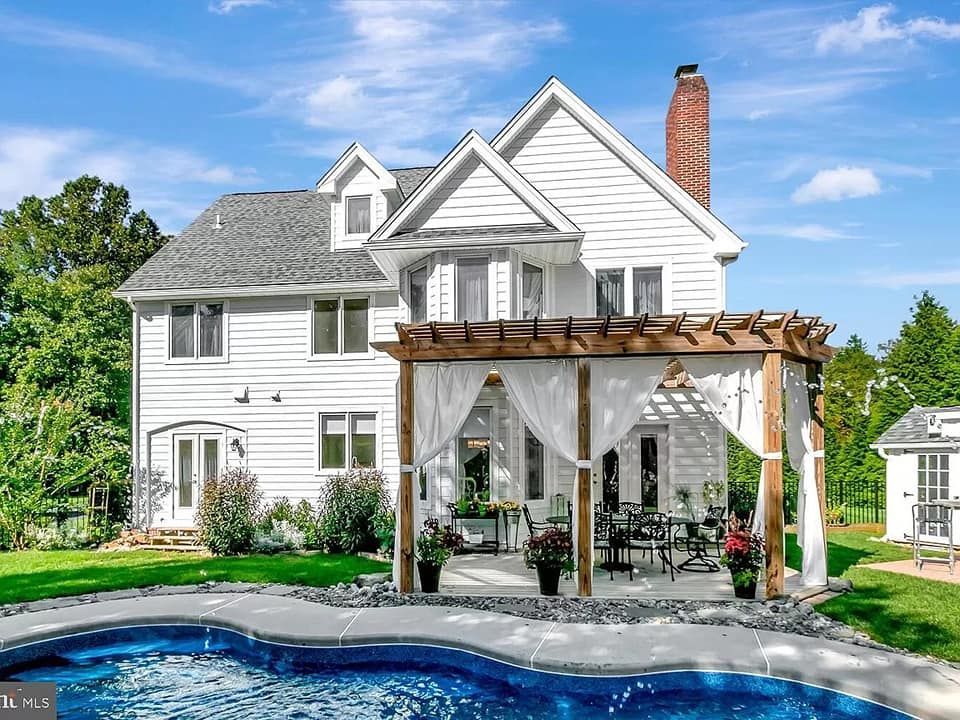 A large white house with a large swimming pool in front of it.