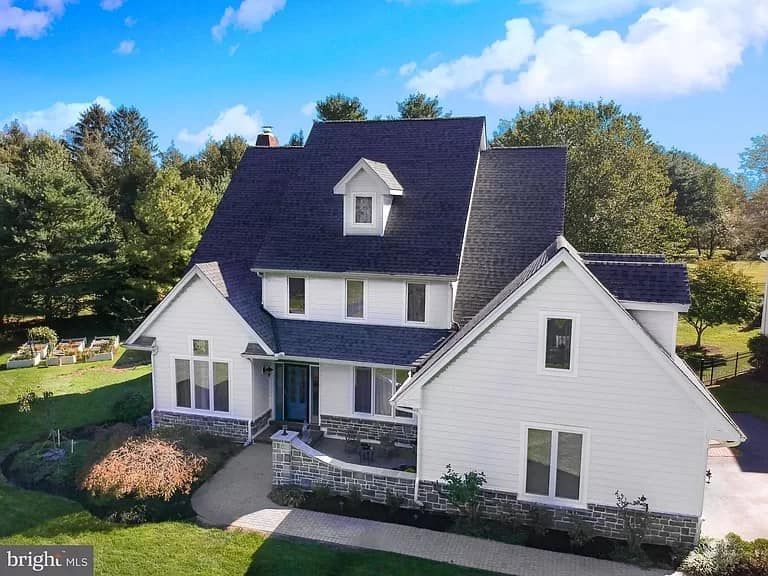 An aerial view of a large white house with a blue roof surrounded by trees.