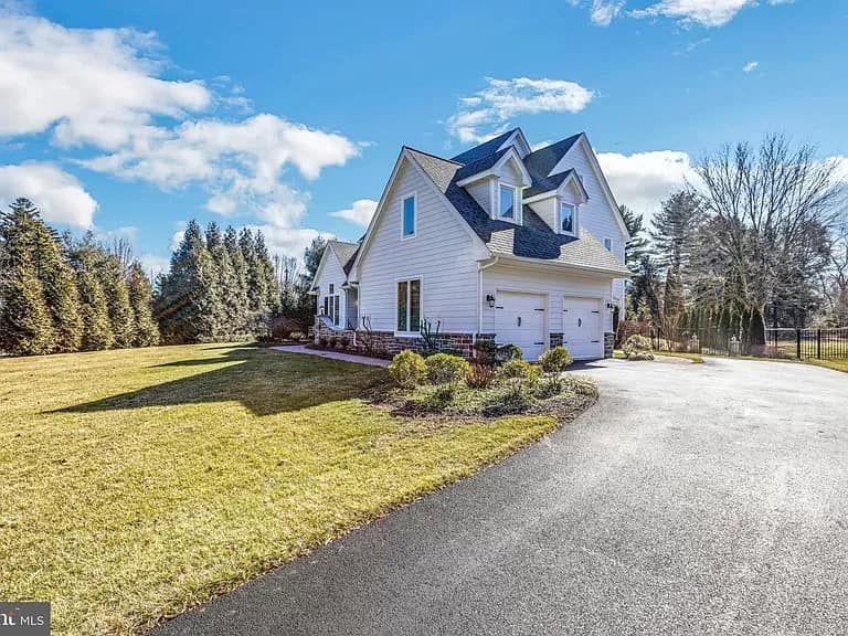 A large white house with a black roof is for sale.