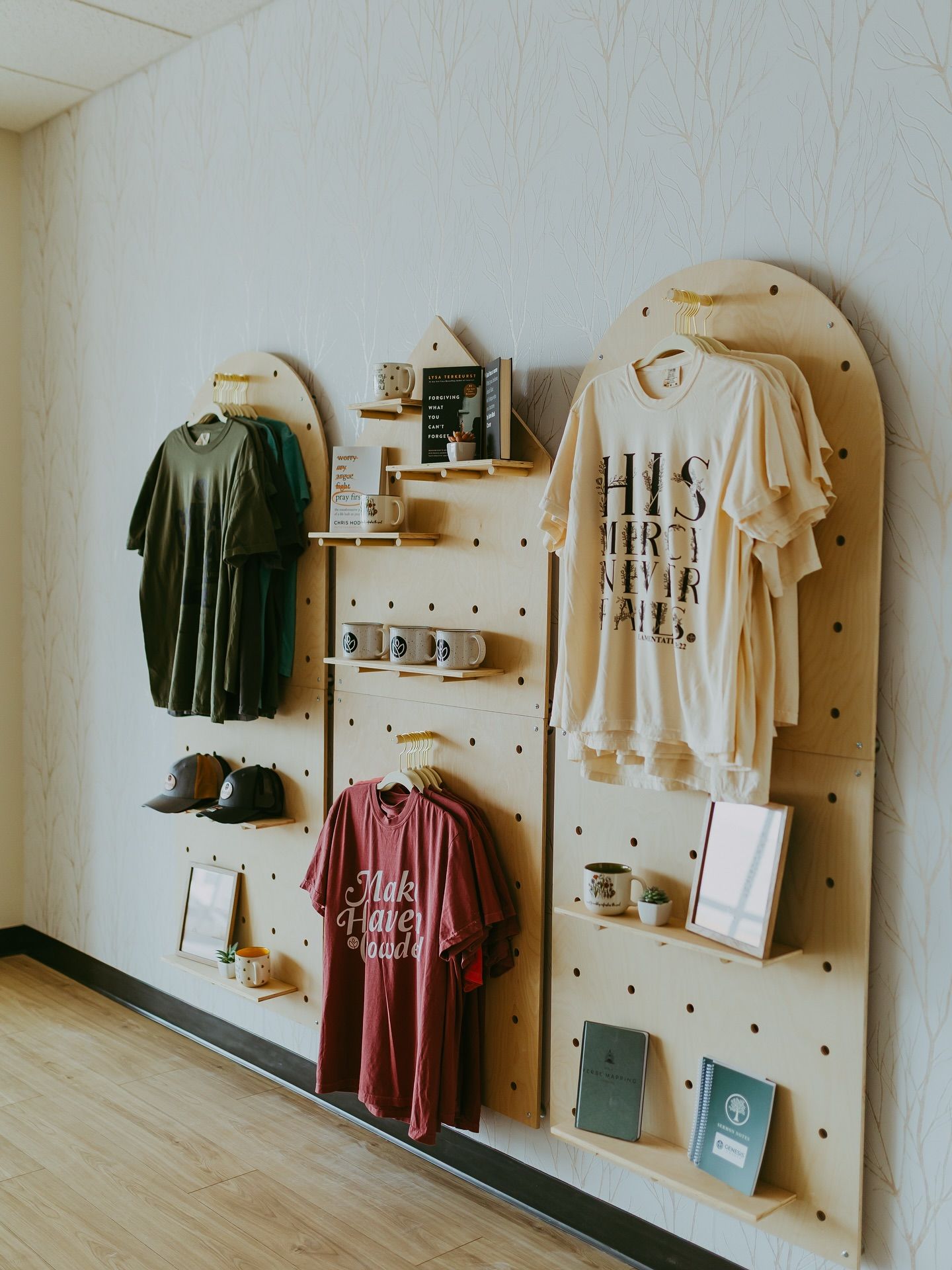 Wooden retail display with t-shirts, mugs, books, and hats.