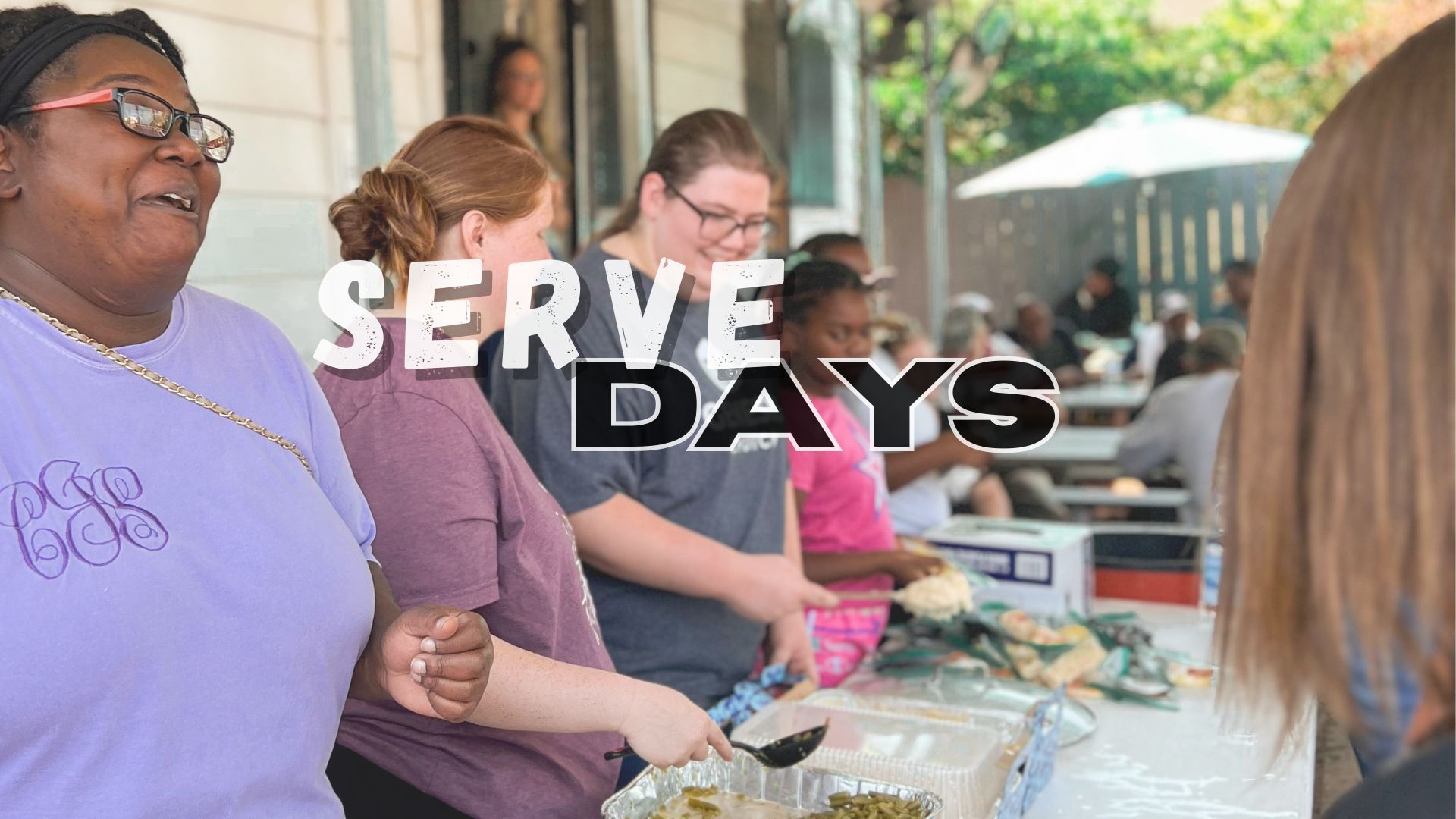 A group of women are standing around a table serving food.