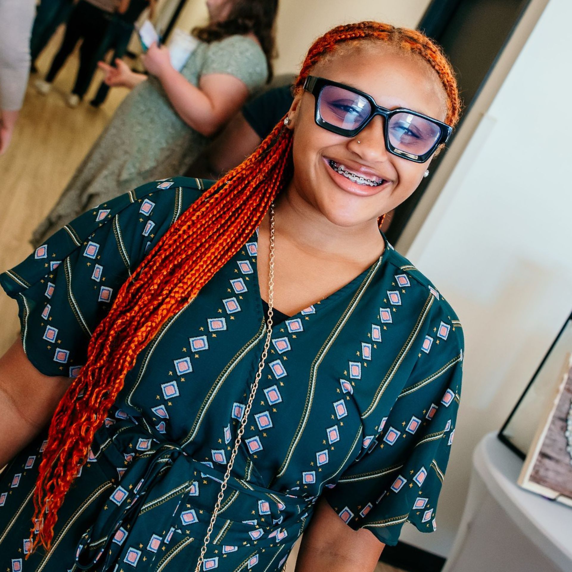 A woman wearing glasses and a green dress smiles for the camera