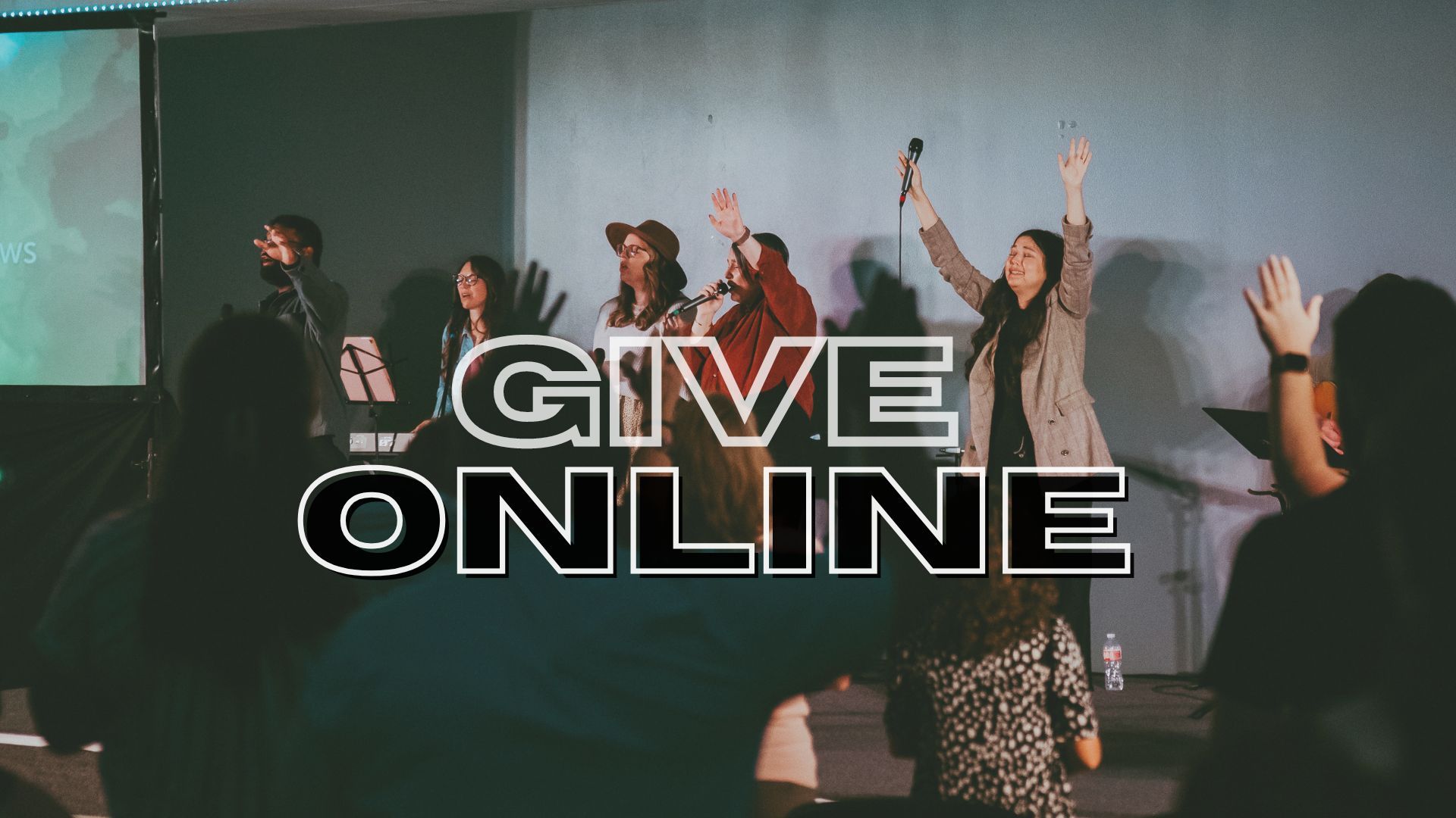 A group of people are standing in front of a screen with the words `` give online '' written on it.