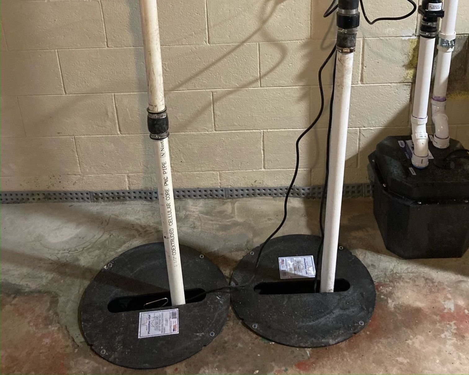 A couple of pipes sitting on top of a concrete floor next to a brick wall.