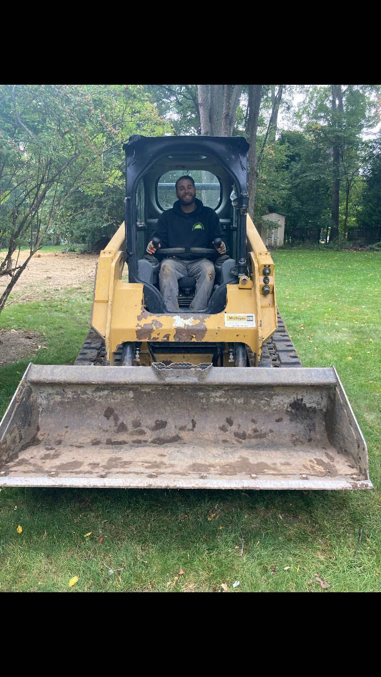 A man is sitting on a bulldozer in a yard.