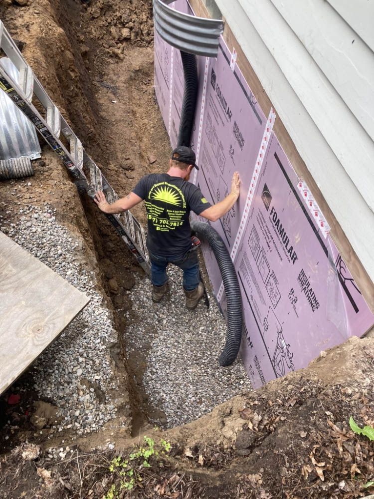 A man is standing in a trench next to a house.