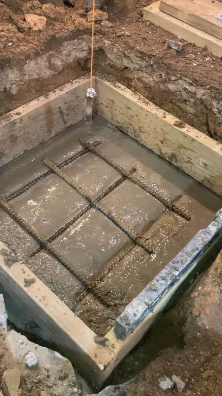 A concrete slab is being poured into a hole in the ground.