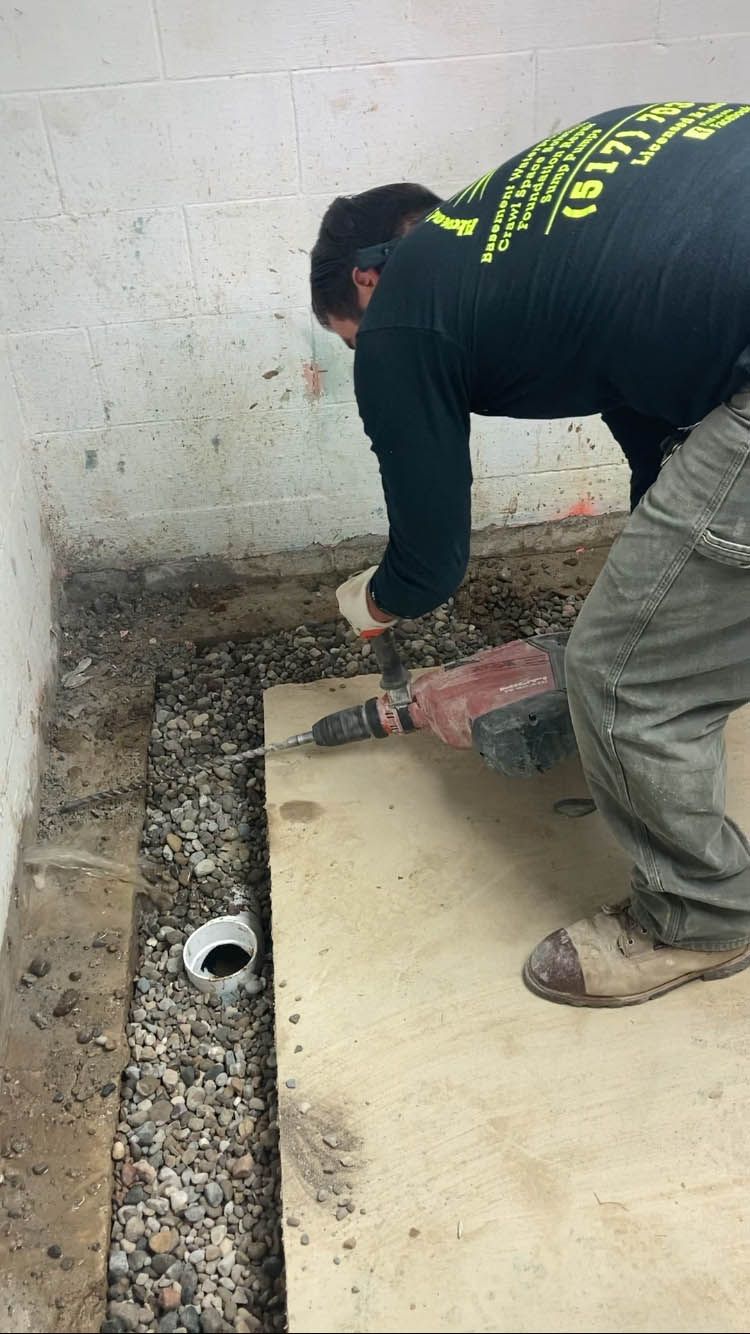 A man is using a hammer to drill a hole in the floor.