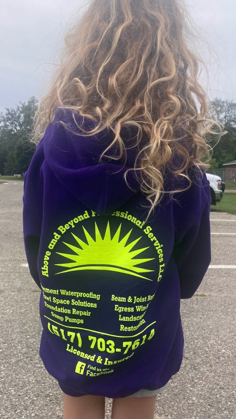 A young girl is wearing a purple hoodie with a yellow sun on the back.