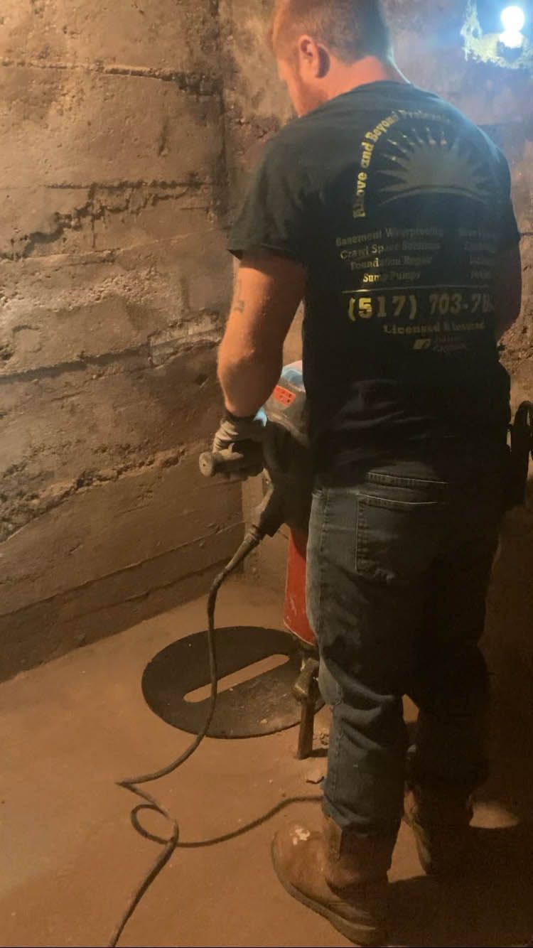 A man is standing in a basement using a vacuum cleaner.