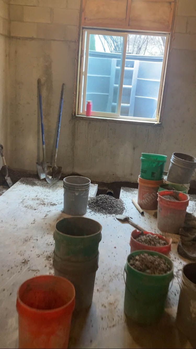 A room with buckets and shovels on the floor and a window.