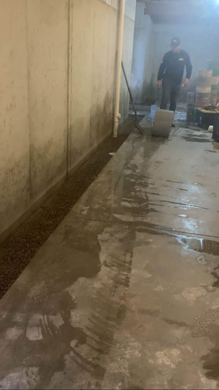 A man is standing in a basement with a broom.