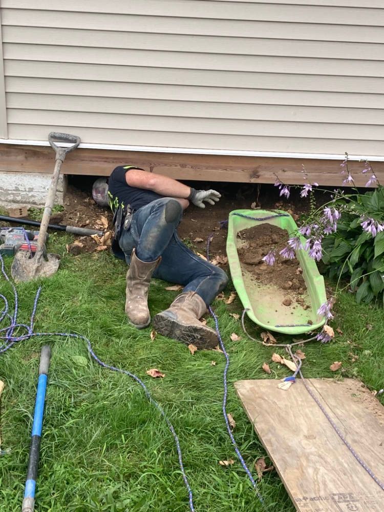 A man is laying on the ground in front of a house.