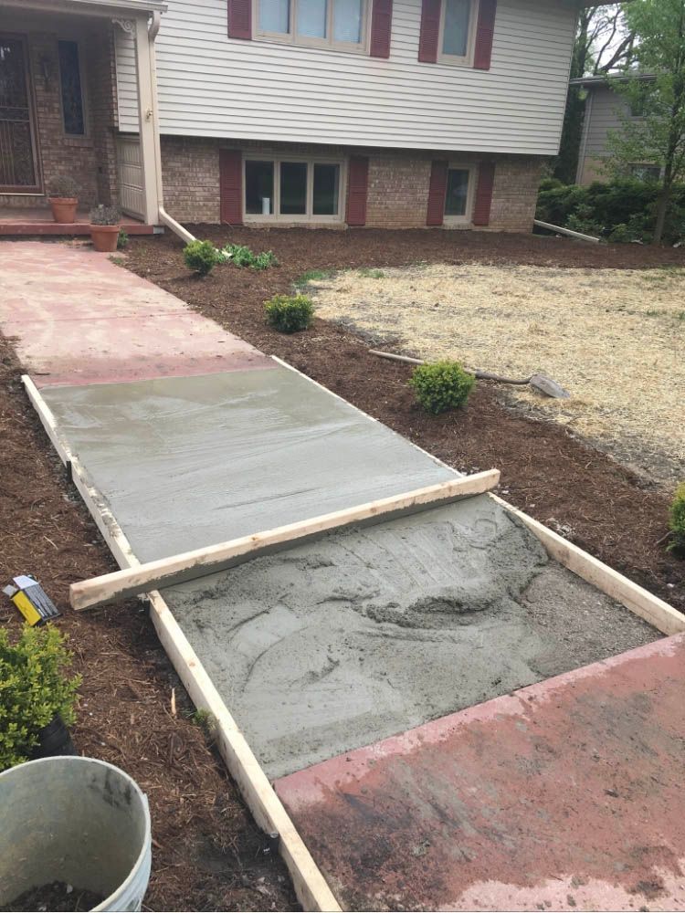 A concrete walkway is being built in front of a house.