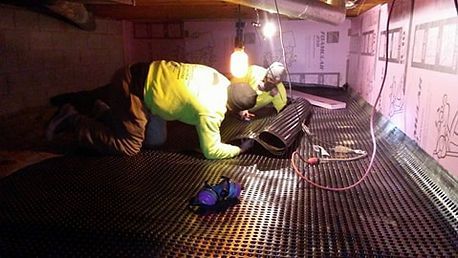 A man is laying on the floor of a basement.