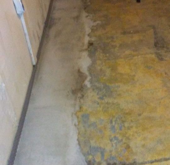 A dirty floor in a room next to a wall.