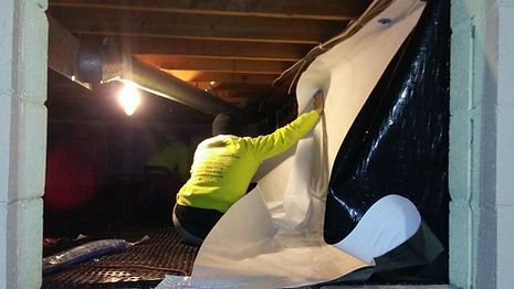 A man in a yellow shirt is peeling off a piece of paper