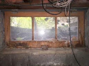 A window in a basement with a lot of wires hanging from the ceiling.