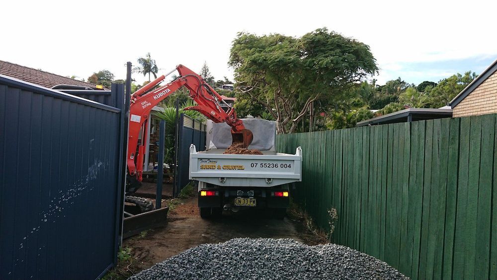 A Dump Truck is Parked in a Driveway Next to a Fence — Twin Towns Sand & Gravel In Pottsville, NSW