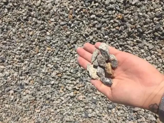 A Person Is Holding A Pile Of Gravel In Their Hand — Twin Towns Sand & Gravel In Byron Bay, NSW