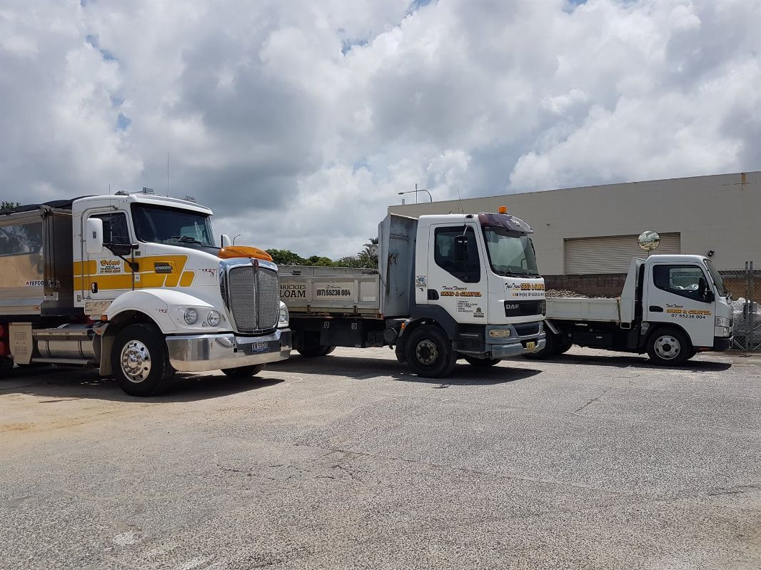 Three Trucks Are Parked Next To Each Other In A Gravel Lot — Twin Towns Sand & Gravel In Kingscliff, NSW