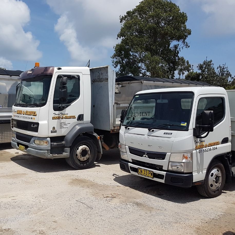 Two White Trucks Are Parked Next To Each Other On A Dirt Road — Twin Towns Sand & Gravel In Byron Bay, NSW