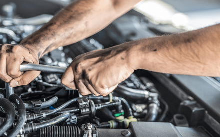 a mechanic doing an auto repair under the hood of a car