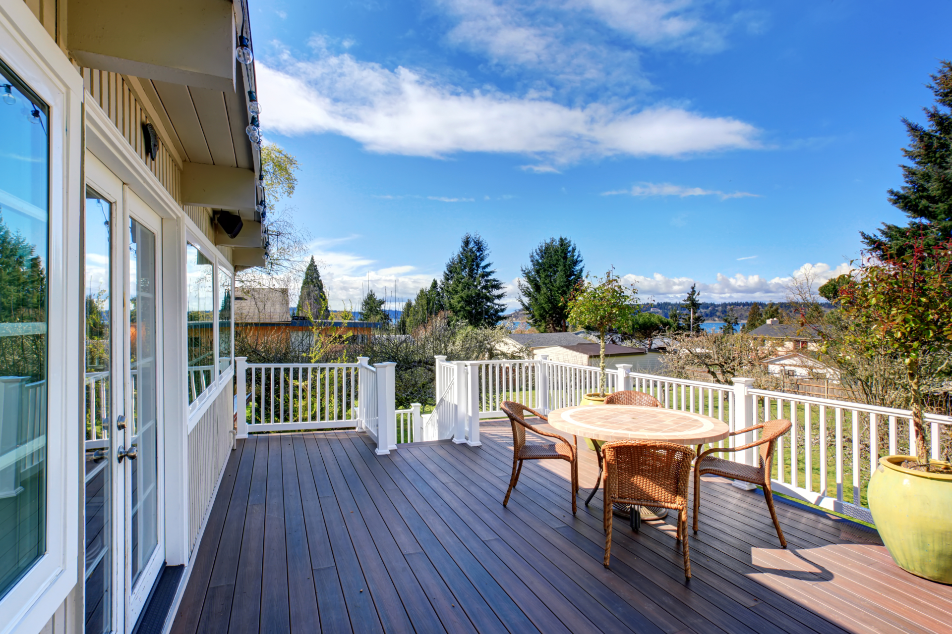 A stunning photo of a beautiful backyard of a home in Chula Vista, California. The deck overlooks the beautiful landscape and other homes in the neighborhood. There are several trees around the deck to add to natural beauty of he photo.