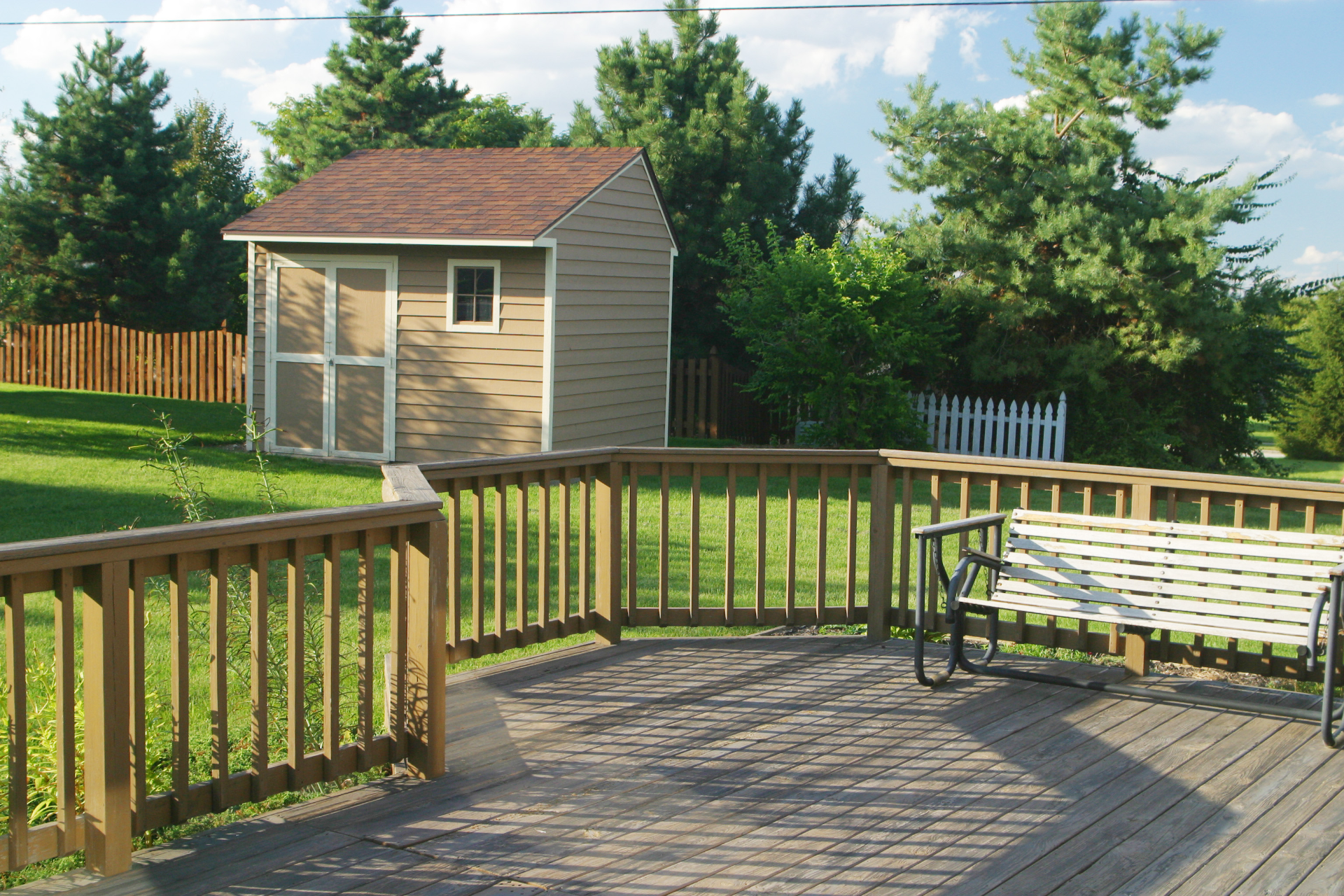 A photo of a smaller and simple deck built in a California house's backyard. The deck is low to the ground but still has a railing for added safety when people walk around.