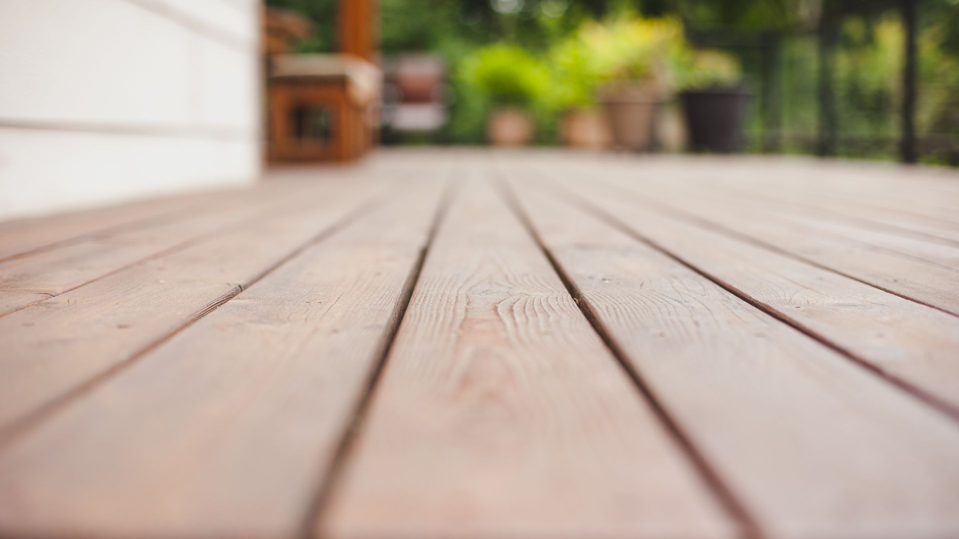 Close-up of a wooden deck with a blurred garden background.