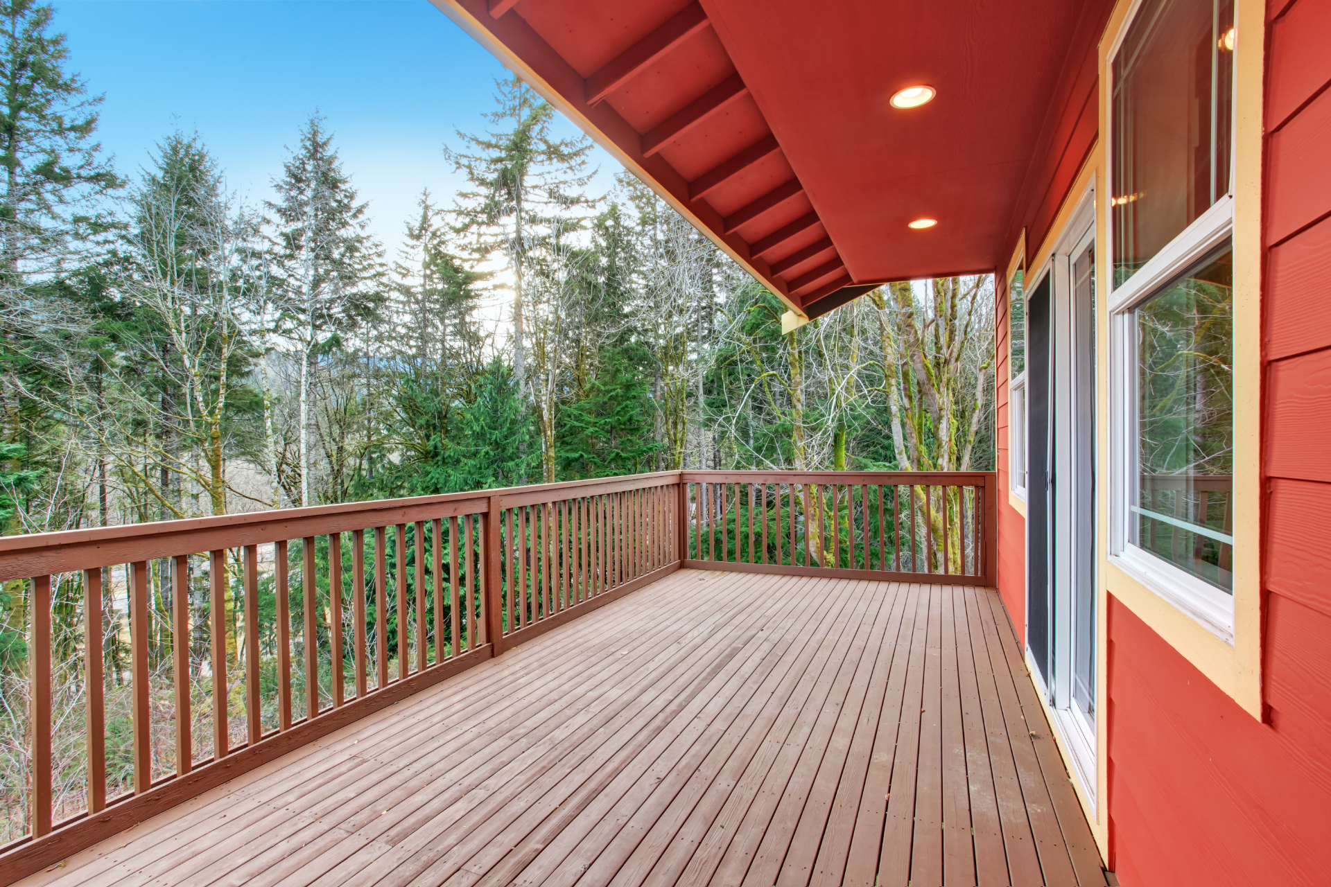 A photo of a newly built deck built by South Bay Deck Pros. The deck is a second-level deck, and an extension of the house roof covers a portion of the deck. The other part is uncovered.