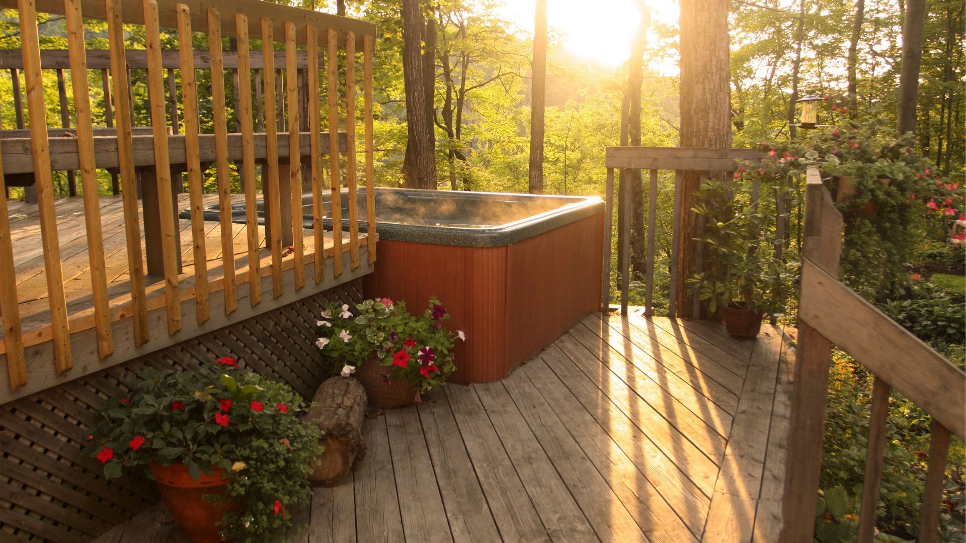 Warm sunset over a spacious deck in St. Paul, featuring a hot tub and lush greenery.