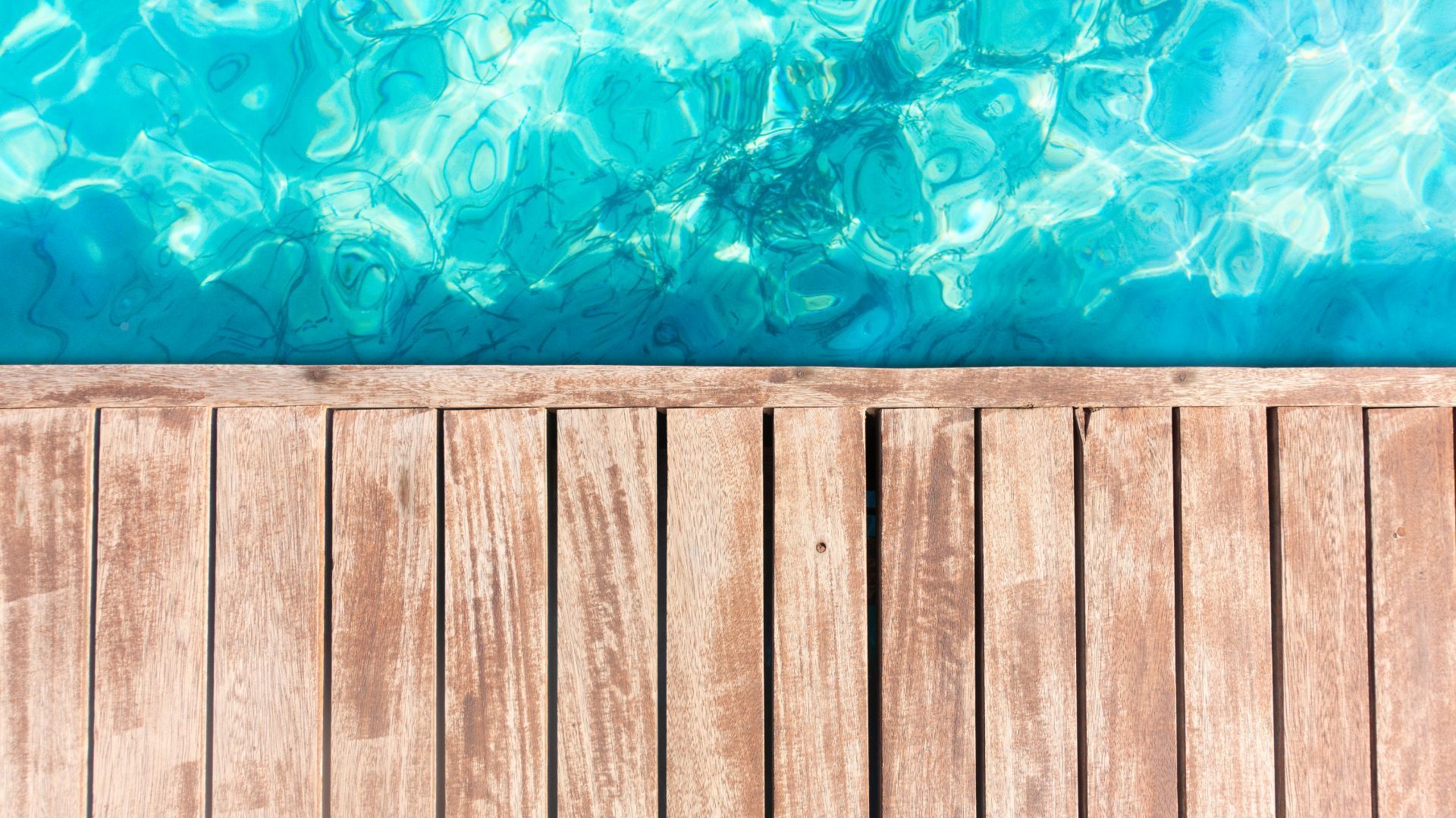 Wooden deck beside a clear, turquoise swimming pool in Chula Vista, CA.