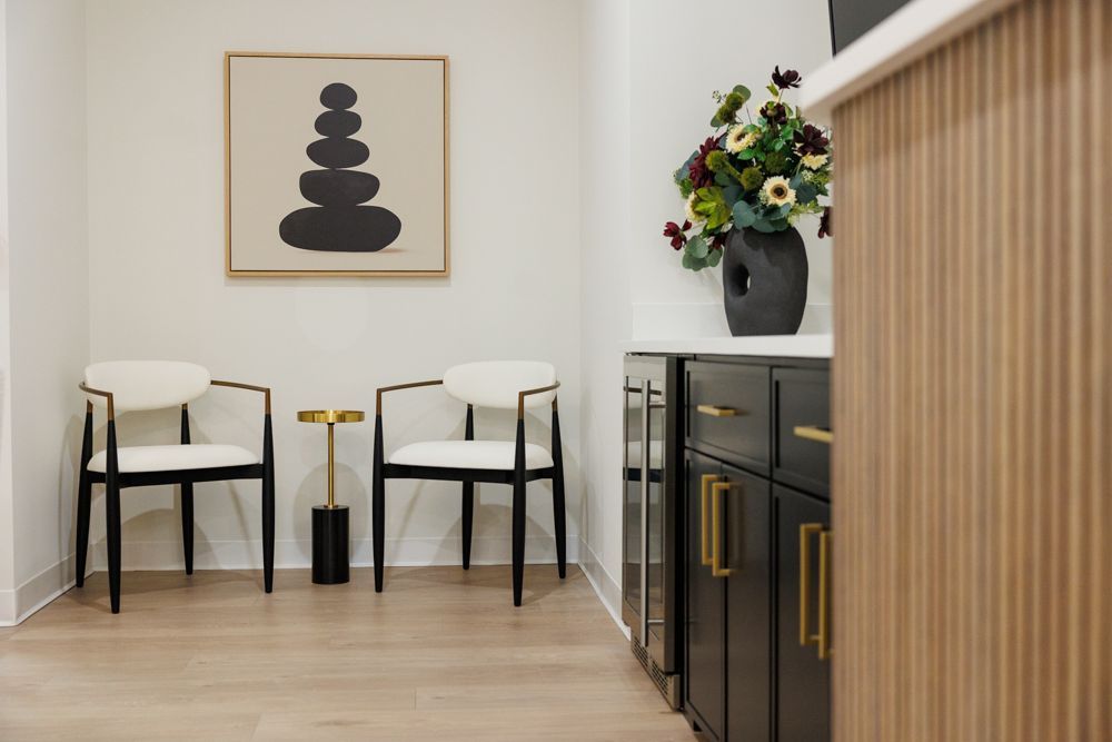 A waiting room with two chairs and a vase of flowers on the counter.
