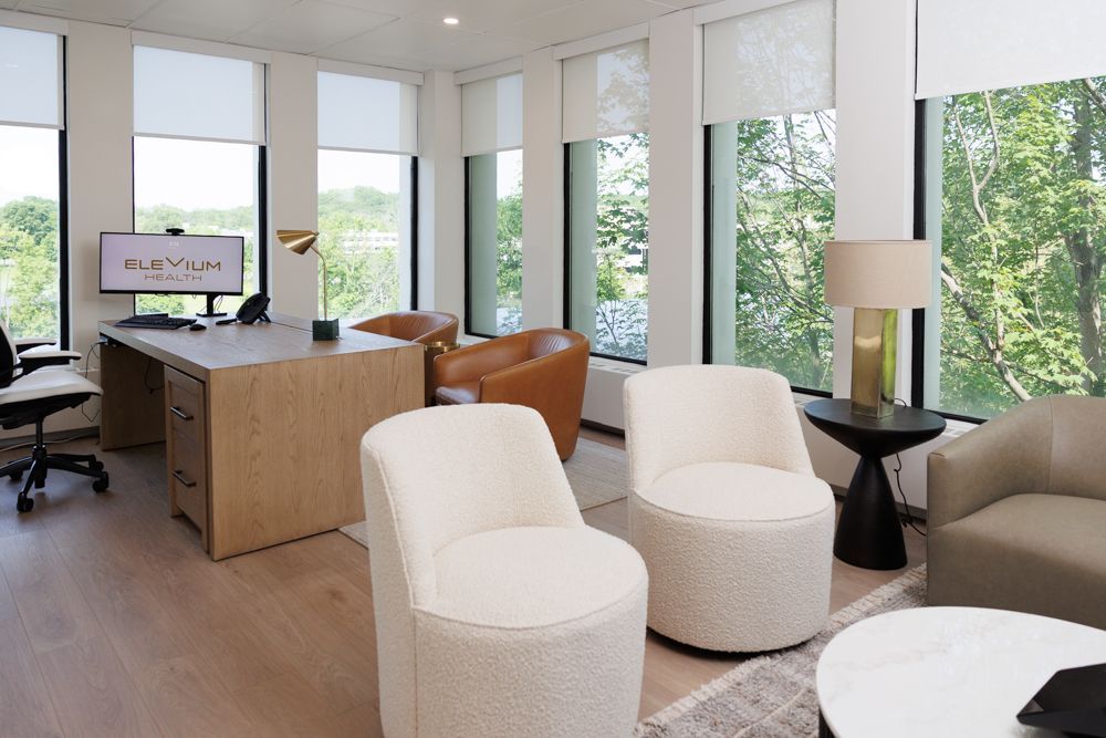 A living room with a desk , chairs , a couch and a table.