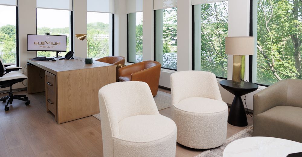 A living room with chairs , a couch , a table and a desk.