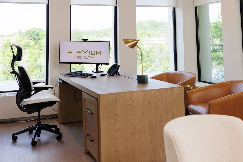 A desk with a computer on it and a chair in an office.
