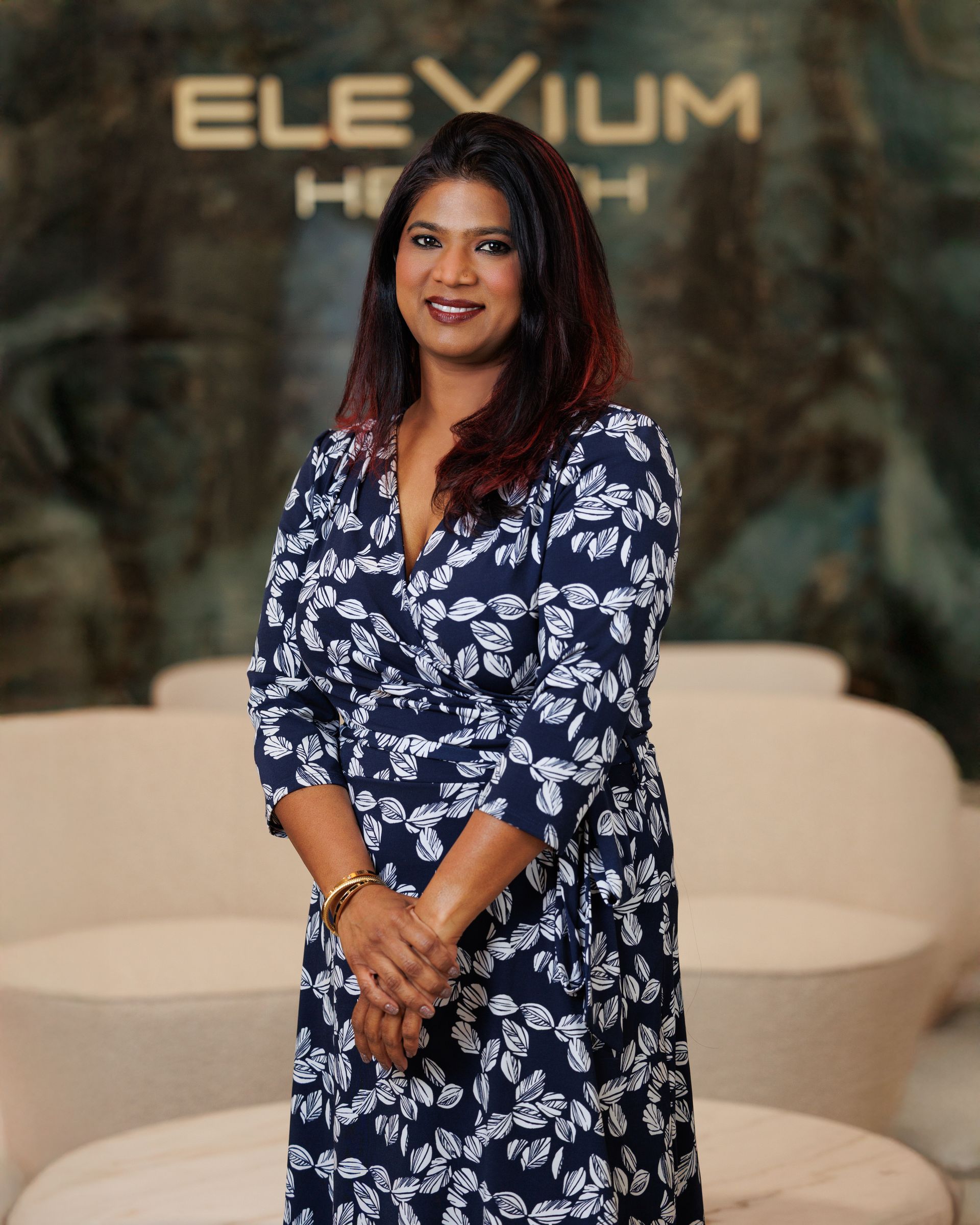 A woman wearing a black jacket and a blue shirt is smiling for the camera.