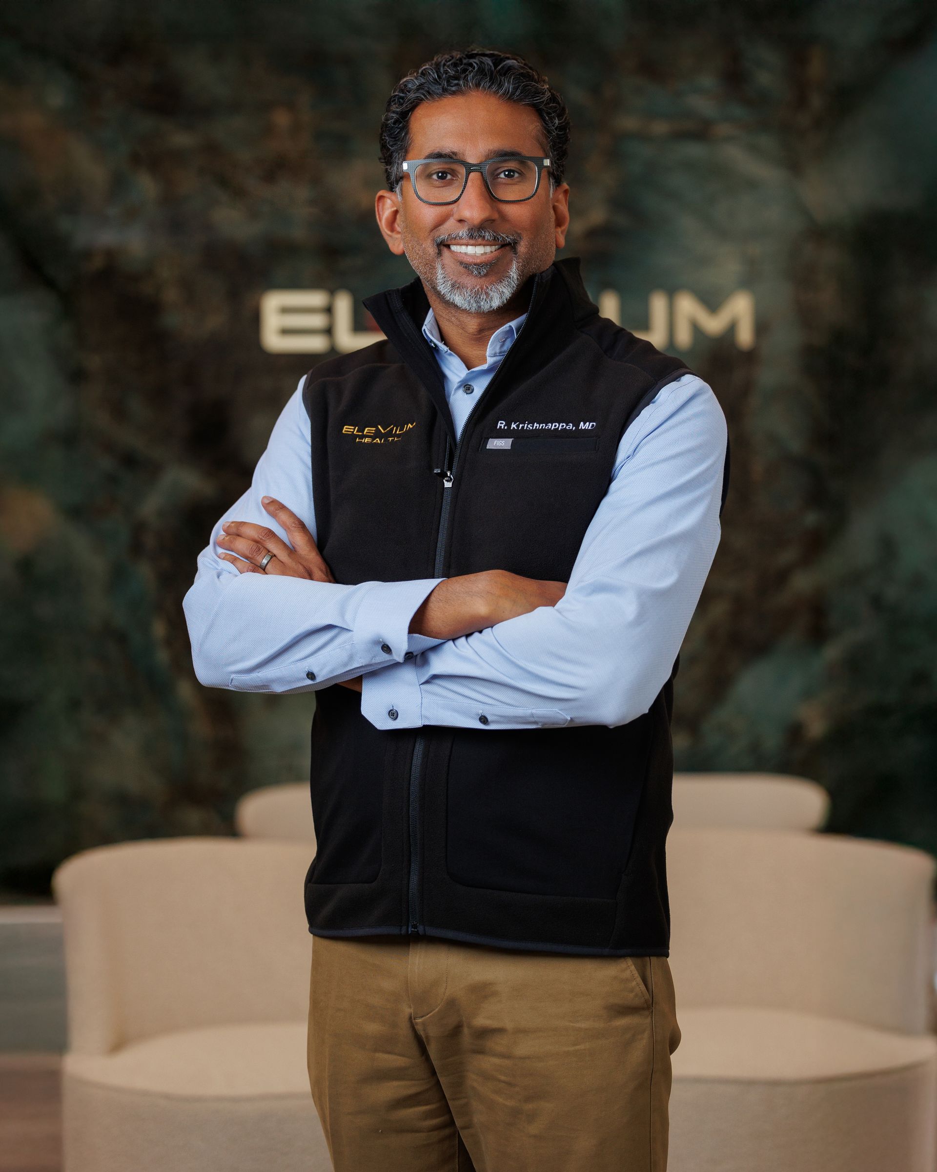 A man wearing glasses and a blue suit is smiling for the camera.