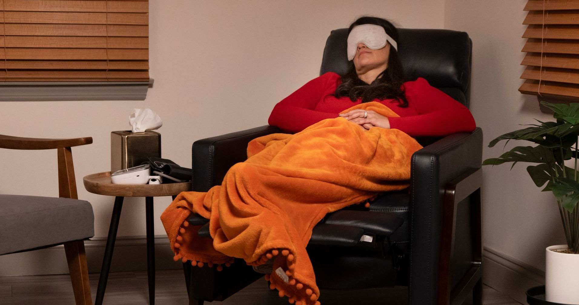 A woman is laying in a chair with a blanket on her head.