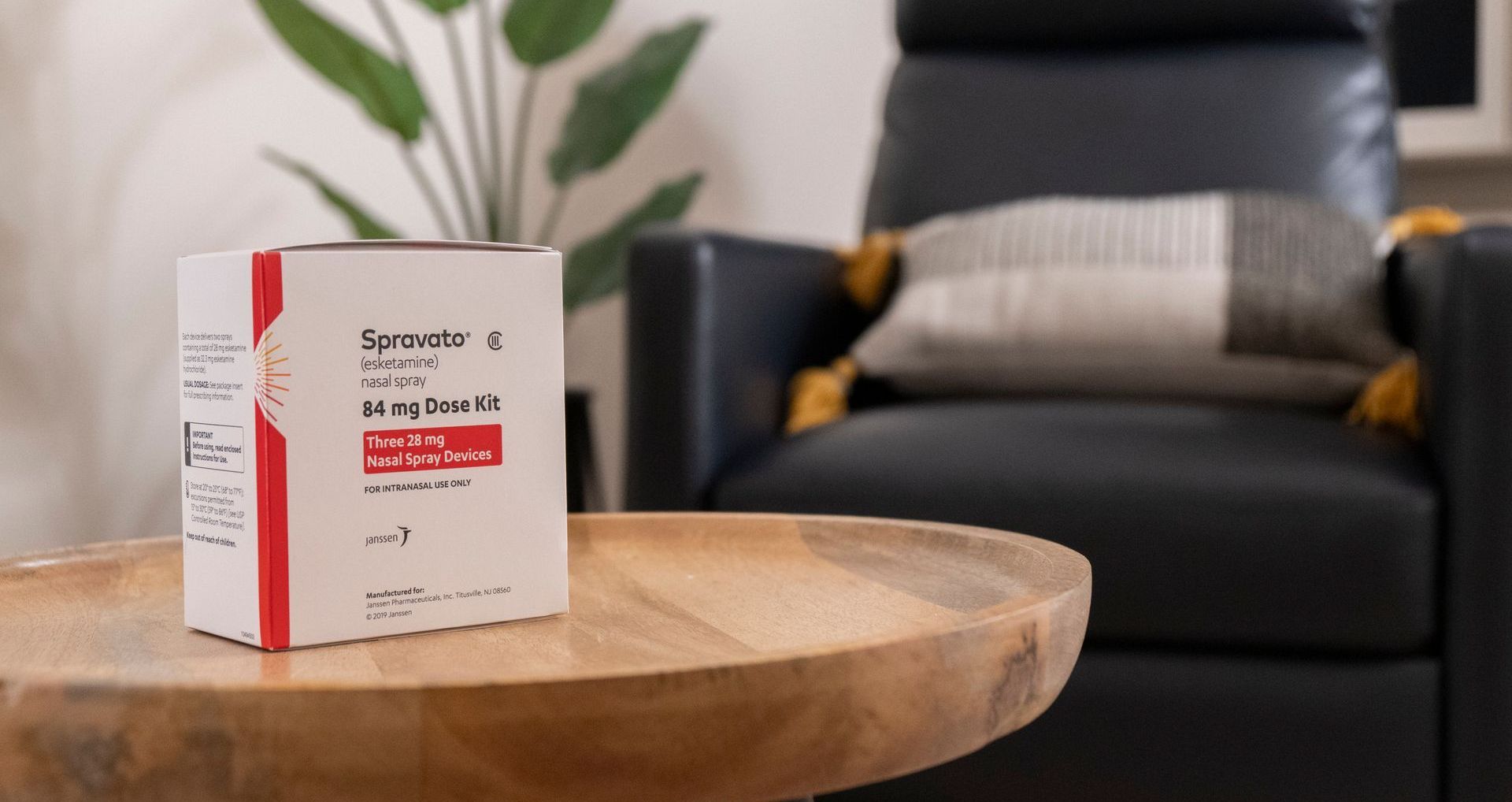 A box of pills is sitting on a wooden table next to a chair.