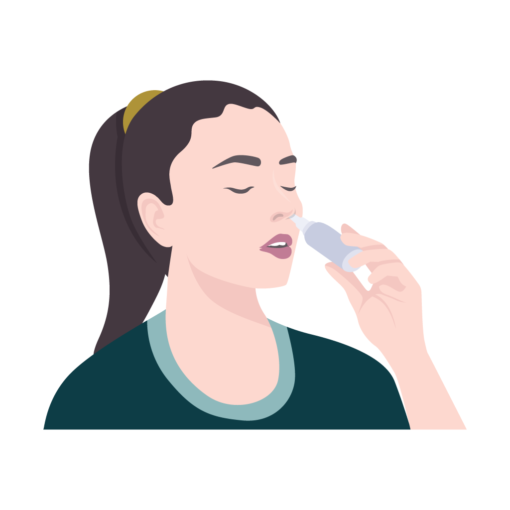 A woman is applying a nasal spray to her nose.