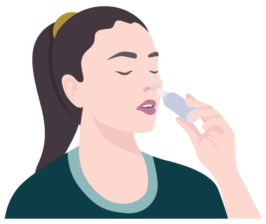 A woman is applying a nasal spray to her nose.