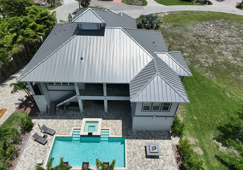 Roofers working on a flat roof with gray material and safety cones.