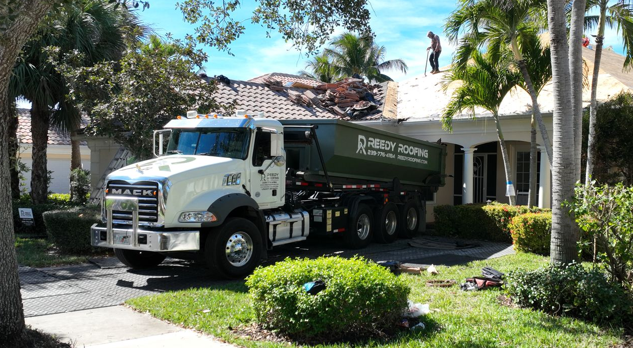 Truck near a house undergoing roof work. Workers on the roof.