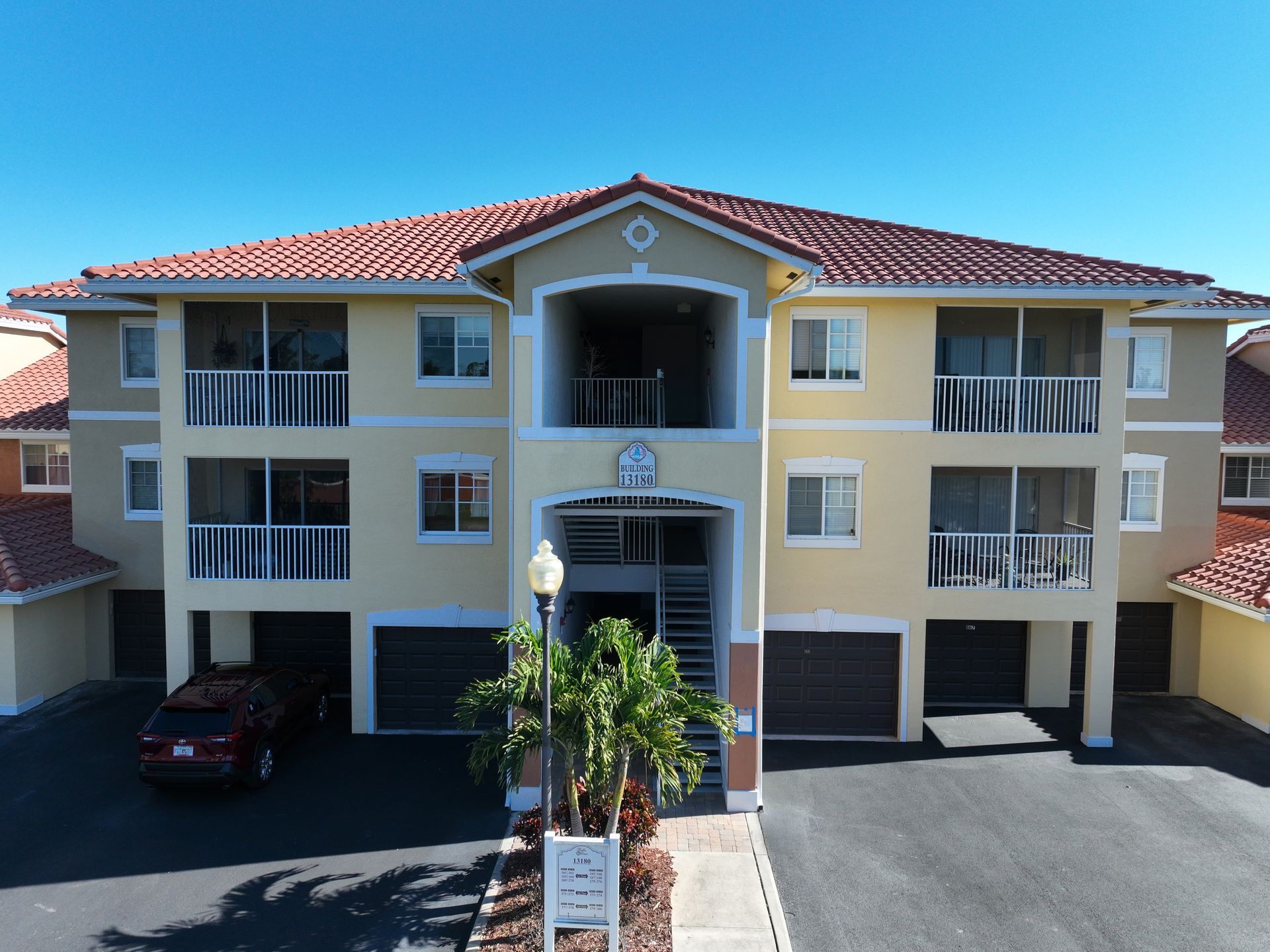 Yellow multi-story condo building with garages, balconies, and red tile roof.