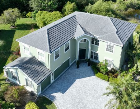 Aerial view of a two-story light green house with a gray tile roof