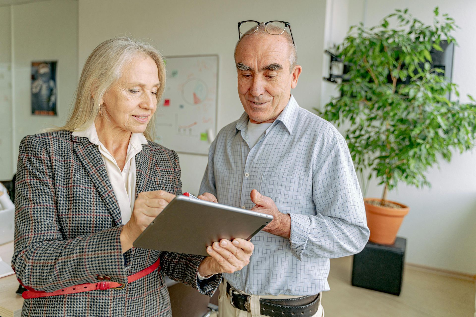 A man and a woman are looking at a tablet together.